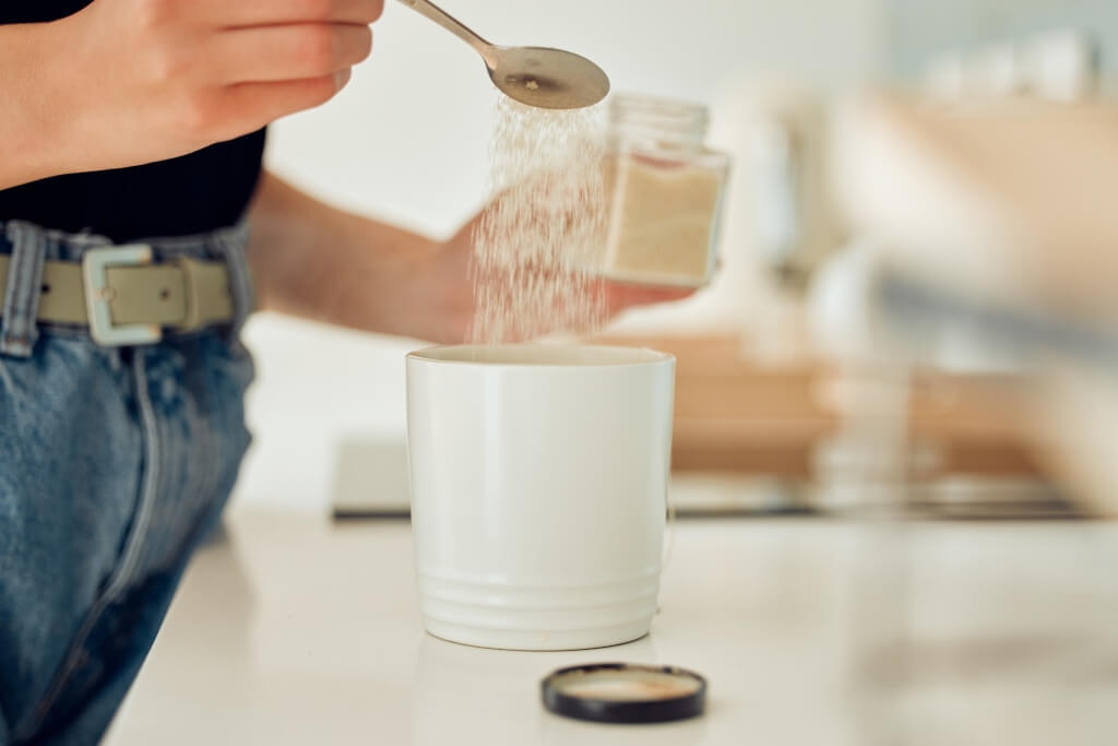 Sugar and Inflammation - Lady adding sugar to their coffee