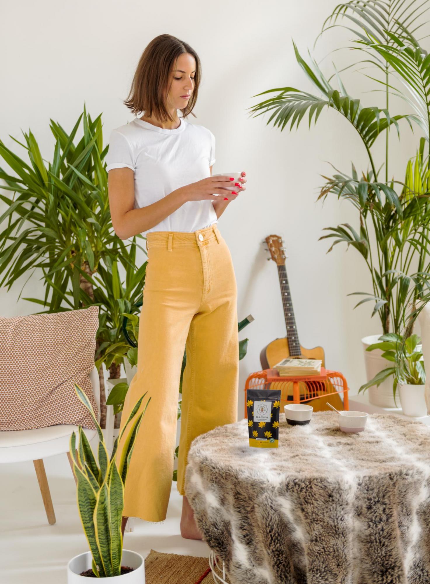 Woman in yellow trousers drinking cbd coffee