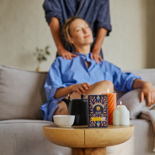 Couple relaxing at home with a box of Cheerful Buddha Lion's Mane Decaffeinated Black Tea, a teapot and candles