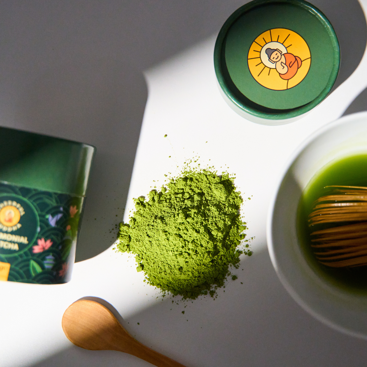 Ceremonial Grade Matcha tube with matcha powder, a wooden spoon and a bamboo whisk