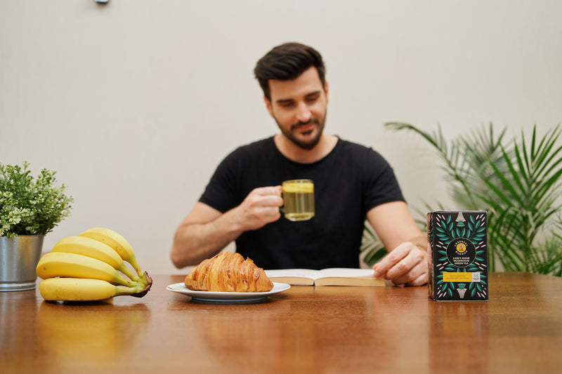Man enjoying a glass of Lion's Mane Green Tea at breakfast