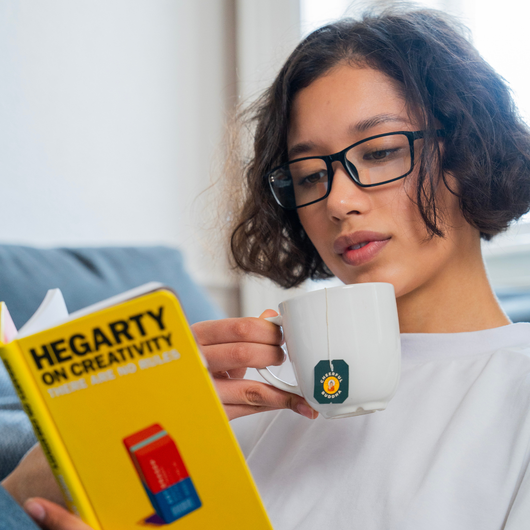 Woman reading a book with a mug of Lion's Mane Green Tea