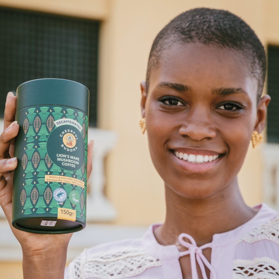 Smiling woman holding up a tube of Lion's Mane Coffee Decaf