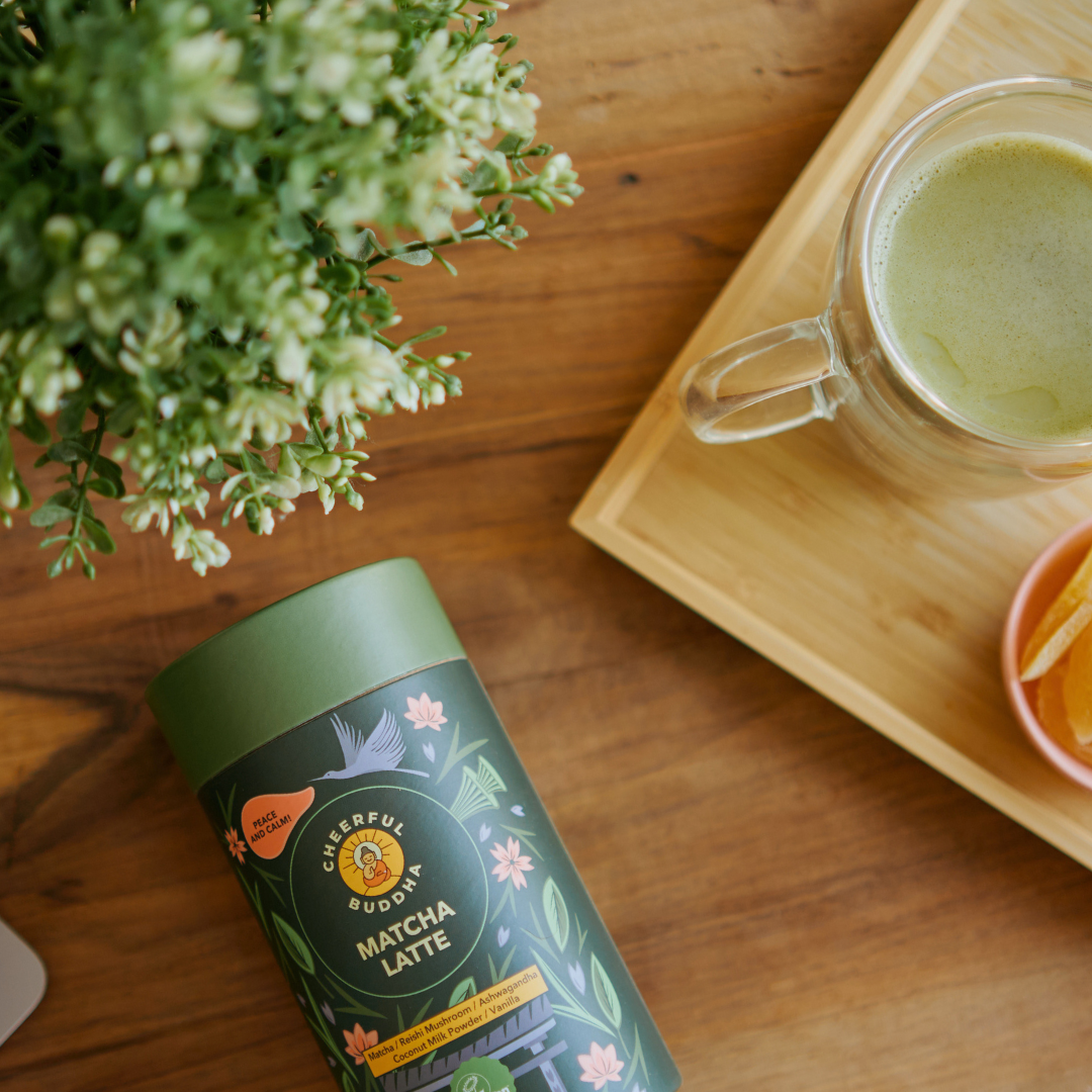 Matcha Latte tube on a wooden table next to a glass of matcha latte