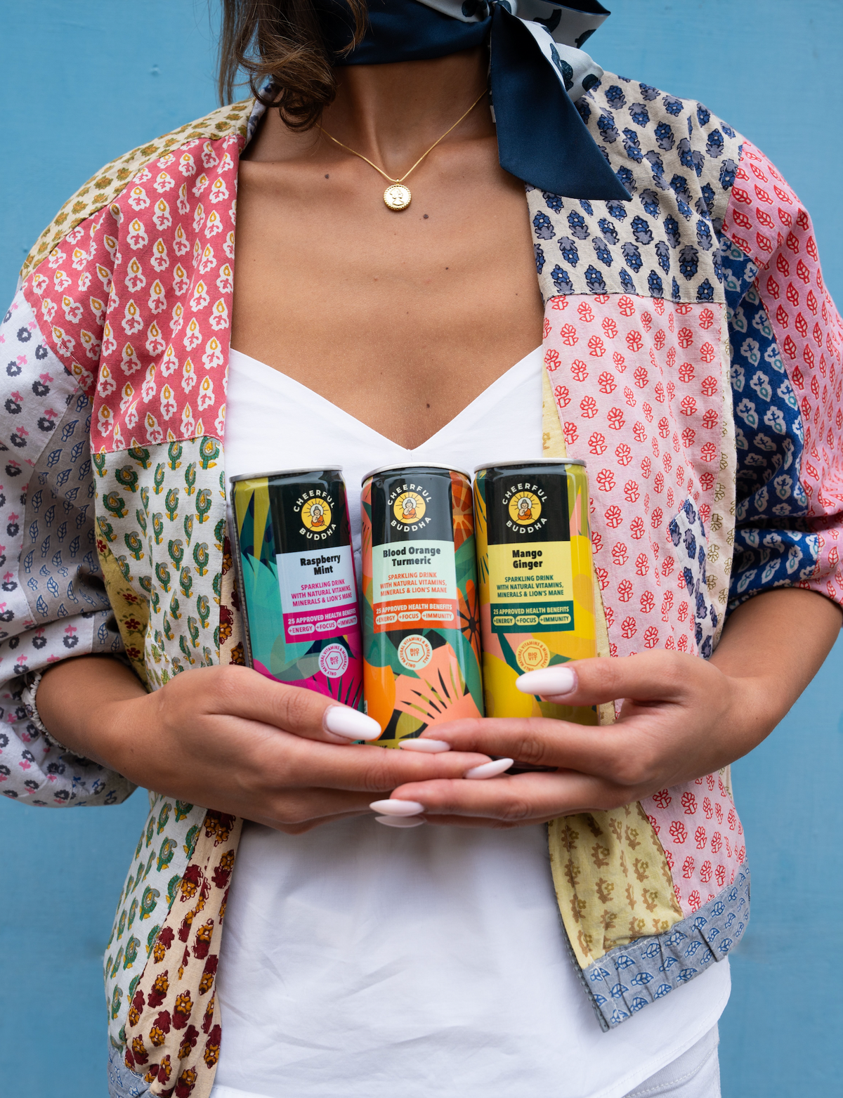 Woman holding Raspberry & Mint, Blood Orange & Turmeric and Mango & Ginger sparkling drink cans