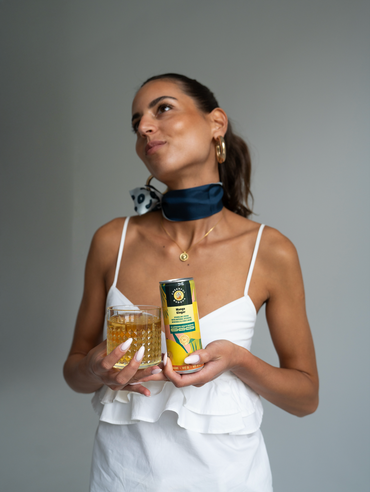 Woman holding a glass and a can of Mango & Ginger sparkling drink
