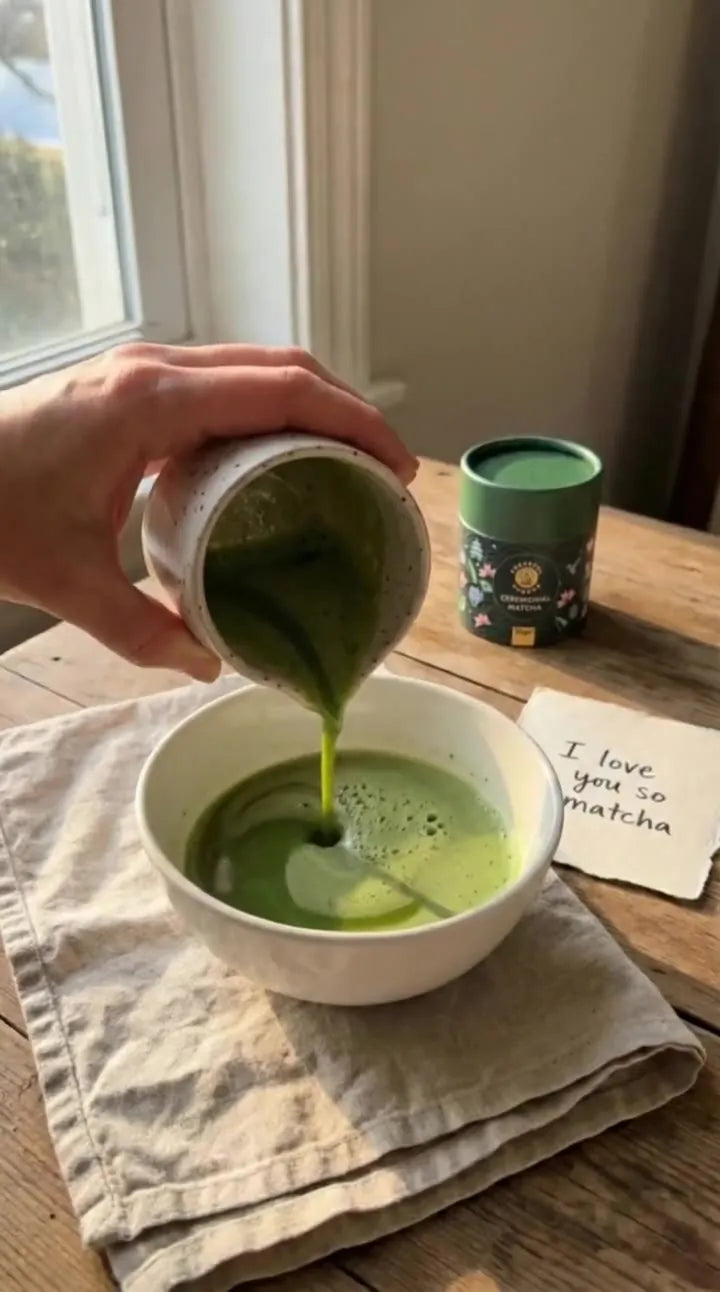 Matcha poured from a small jug into a white bowl, with a Cheerful Buddha matcha tube on the table