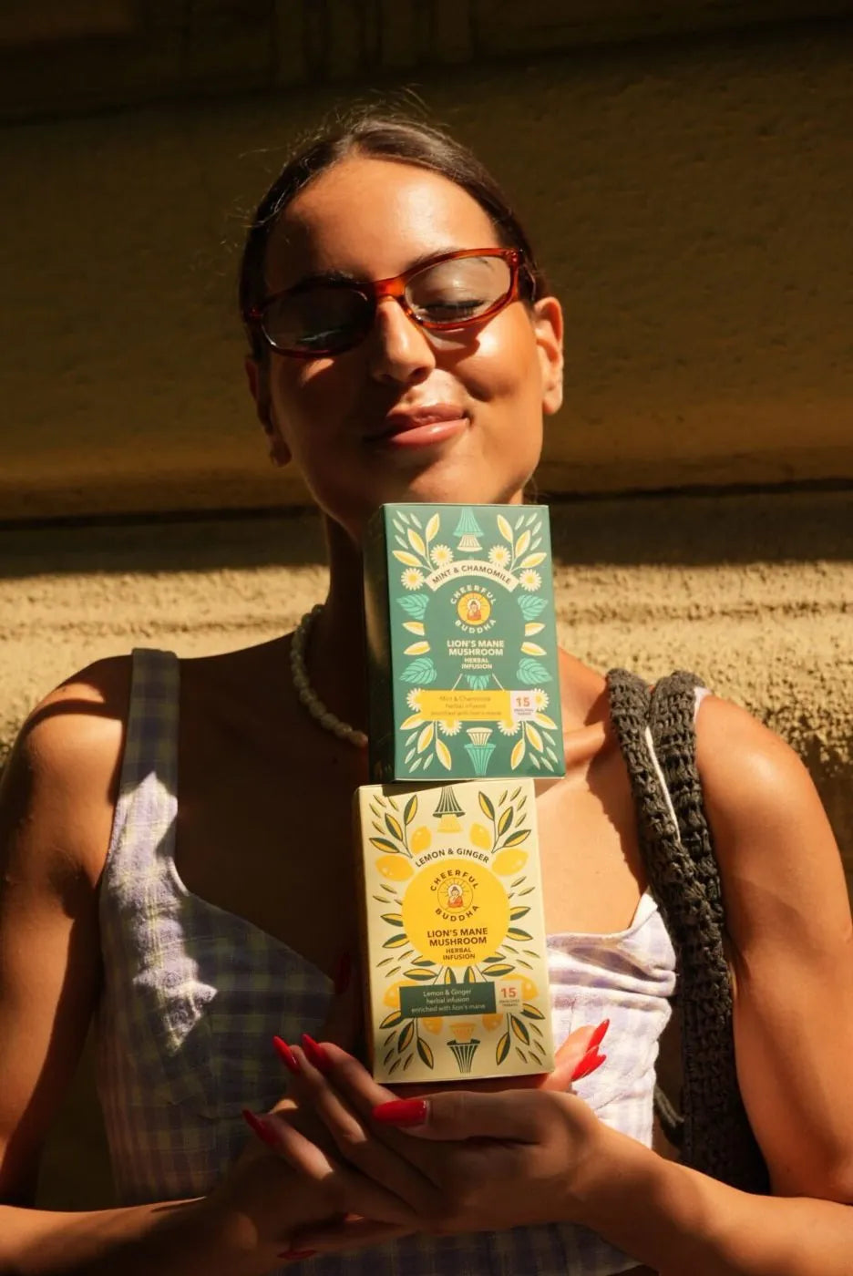 Woman in the sun holding Lion's Mane tea boxes