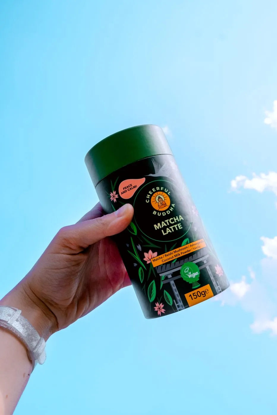 Matcha Latte tube held up against a blue sky