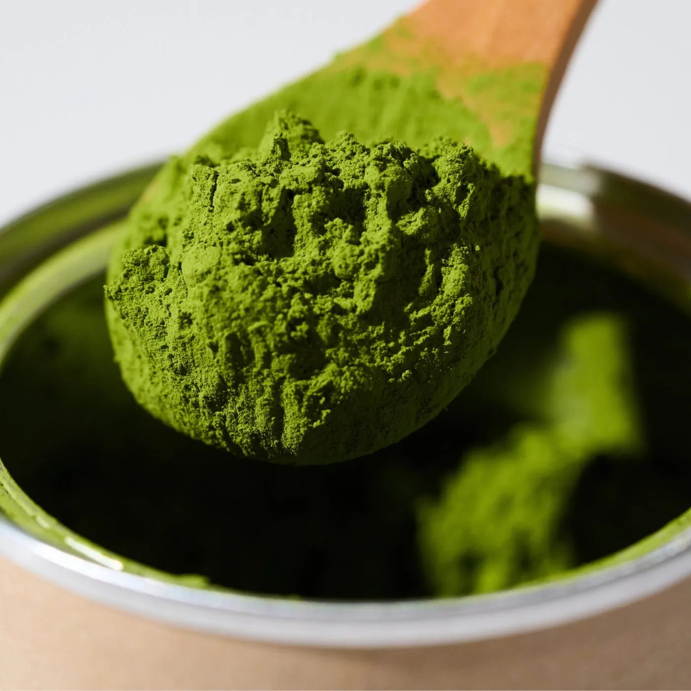 Wooden scoop of bright green ceremonial grade matcha powder