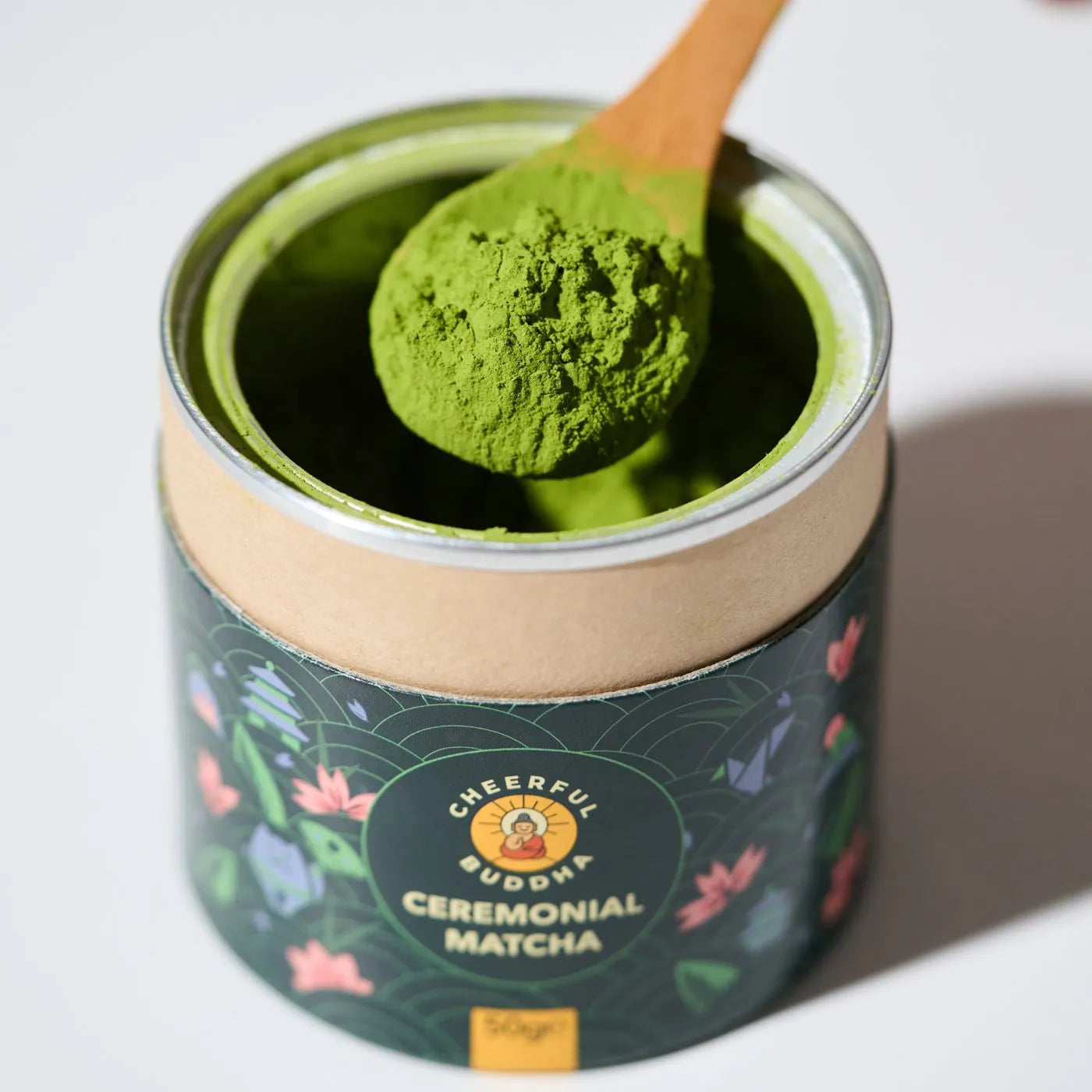 Open Ceremonial Grade Matcha tube with a wooden scoop of bright green matcha powder